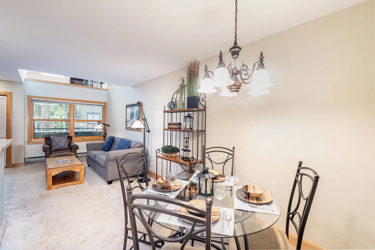 A beautifully set dining table, comfortable living area, and decorative shelving unit combine to create an inviting, multi-functional space. The setup is perfect for shared meals, relaxing after adventures, and making lasting memories.