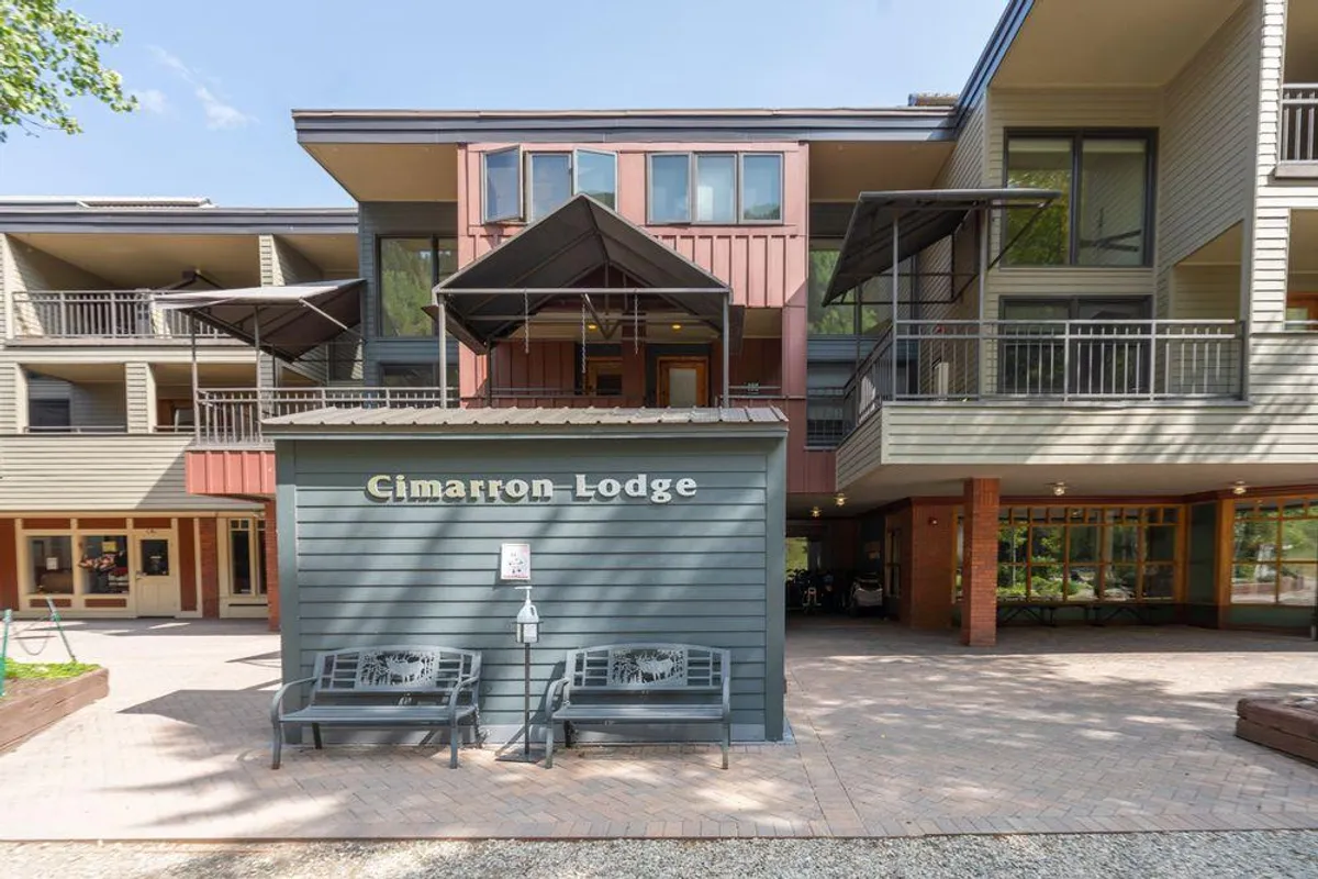 The exterior of Cimarron Lodge, with its prominent sign, balconies, and communal benches, inviting guests to relax outdoors. The lodge’s welcoming façade connects the property to its vibrant mountain surroundings.